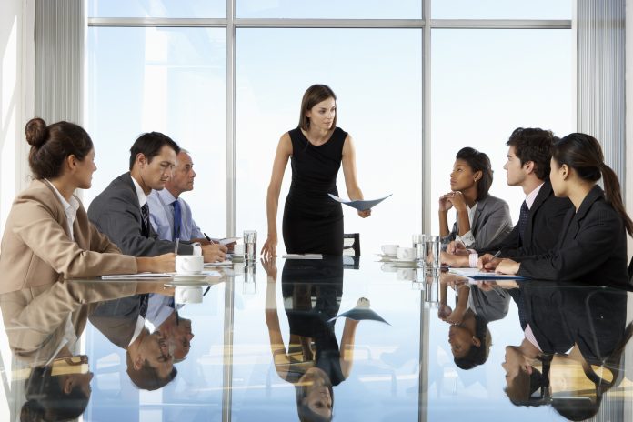 Group Of Business People Having Board Meeting Around Glass Table La mujer directiva hace más rentable la empresa
